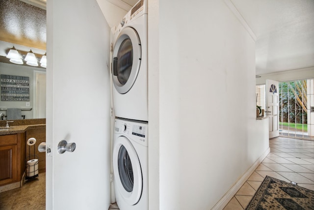 clothes washing area with light tile patterned floors, stacked washer and dryer, and crown molding