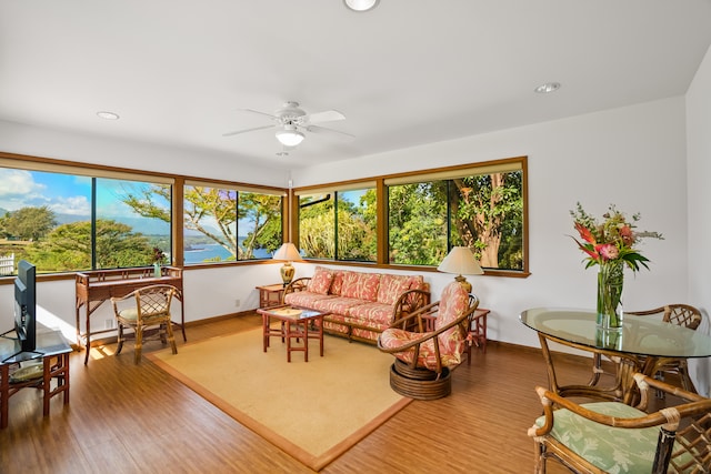 living room with ceiling fan, wood-type flooring, and a healthy amount of sunlight