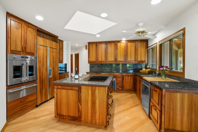 kitchen featuring stainless steel appliances, a skylight, light wood-type flooring, and a kitchen island