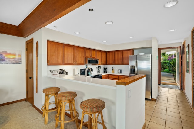 kitchen featuring a kitchen bar, kitchen peninsula, appliances with stainless steel finishes, and light tile patterned flooring