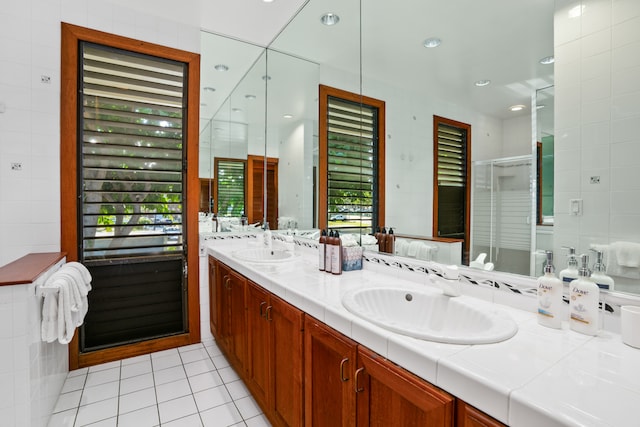 bathroom with vanity, a healthy amount of sunlight, tile patterned floors, and tile walls