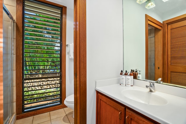 bathroom featuring tile patterned floors, vanity, toilet, a skylight, and a shower with shower door