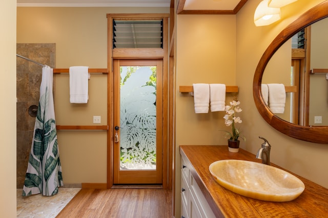 bathroom with ornamental molding, curtained shower, wood-type flooring, and vanity