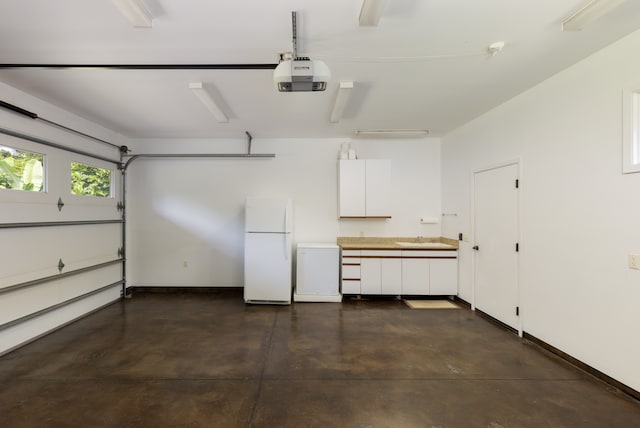 garage featuring sink, white refrigerator, and a garage door opener