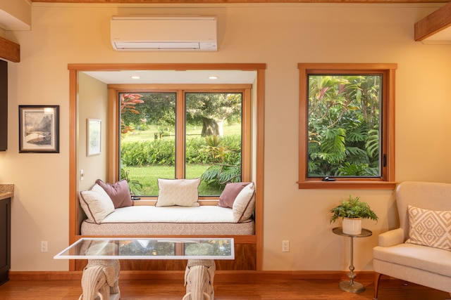 living area with hardwood / wood-style floors and a wall mounted AC