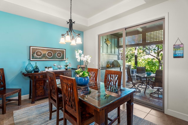 dining room with a raised ceiling, light tile patterned floors, ornamental molding, and an inviting chandelier