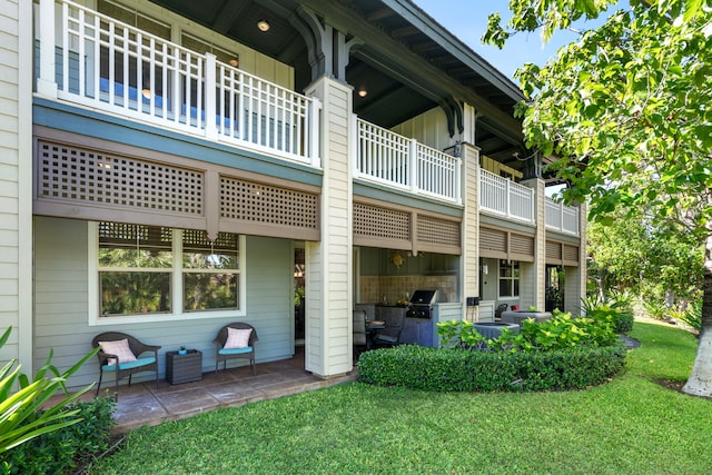 rear view of house featuring a patio, a balcony, area for grilling, and a lawn