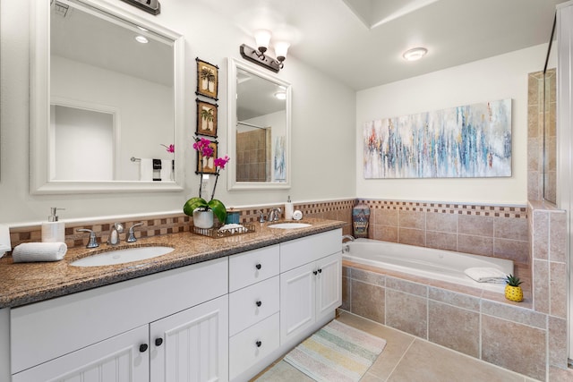 bathroom featuring tile patterned flooring, vanity, and tiled tub