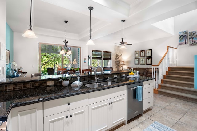 kitchen with stainless steel dishwasher, dark stone counters, sink, decorative light fixtures, and white cabinets