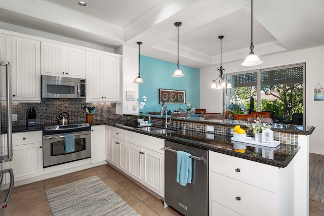 kitchen featuring pendant lighting, white cabinets, sink, a tray ceiling, and stainless steel appliances