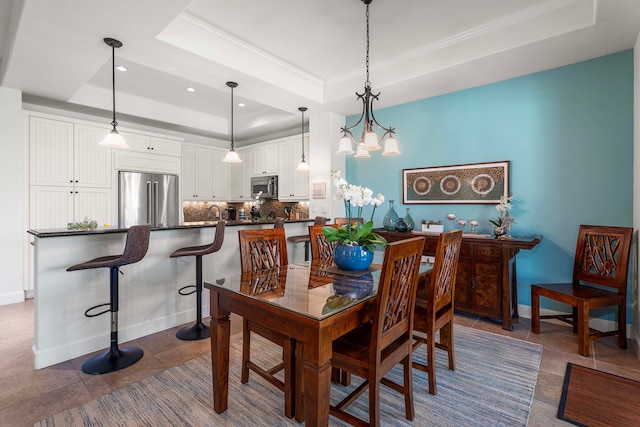 dining space with ornamental molding, a tray ceiling, dark tile patterned floors, and a notable chandelier