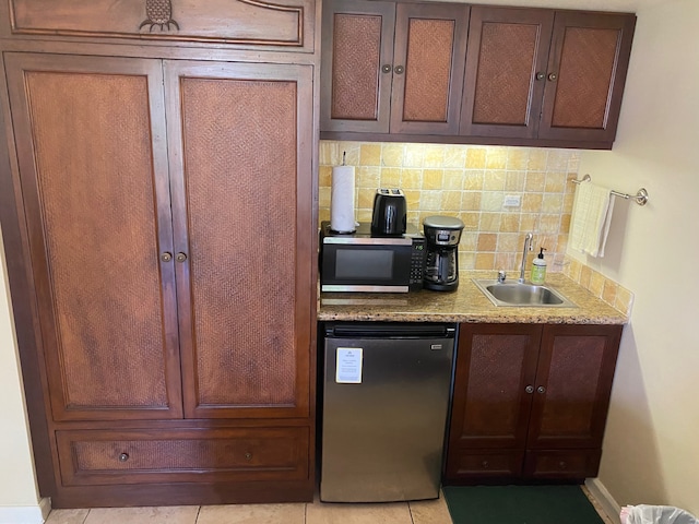 kitchen with sink, appliances with stainless steel finishes, tasteful backsplash, light stone countertops, and light tile patterned floors