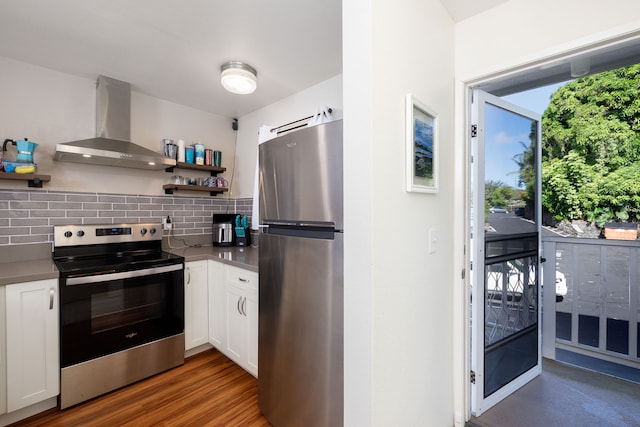 kitchen featuring dark hardwood / wood-style flooring, wall chimney exhaust hood, tasteful backsplash, white cabinetry, and appliances with stainless steel finishes