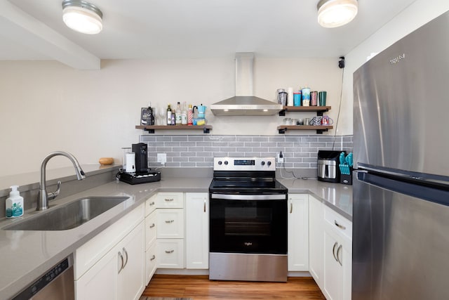 kitchen with white cabinetry, appliances with stainless steel finishes, exhaust hood, sink, and light hardwood / wood-style floors