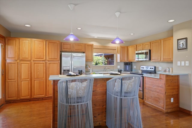 kitchen featuring sink, pendant lighting, a center island, light hardwood / wood-style floors, and stainless steel appliances