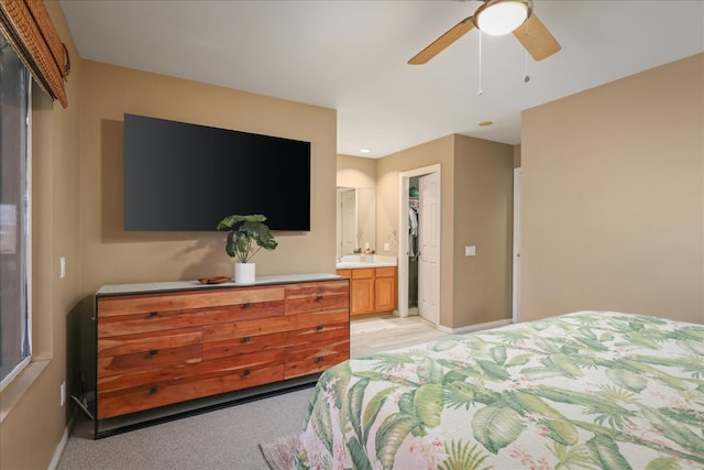 carpeted bedroom featuring a closet, ensuite bath, ceiling fan, and sink