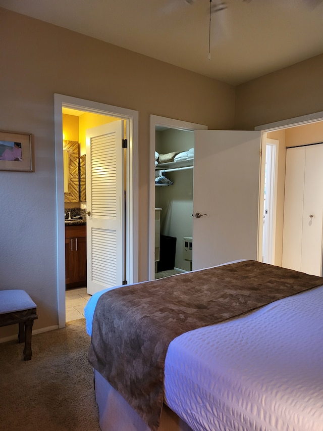 bedroom with ensuite bathroom and light colored carpet