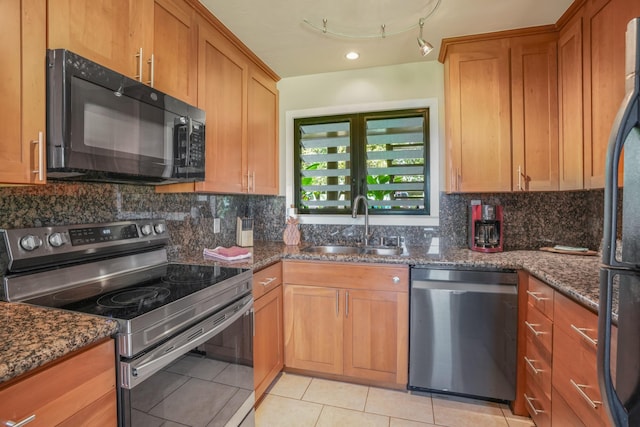 kitchen with light tile patterned flooring, dark stone counters, sink, and black appliances