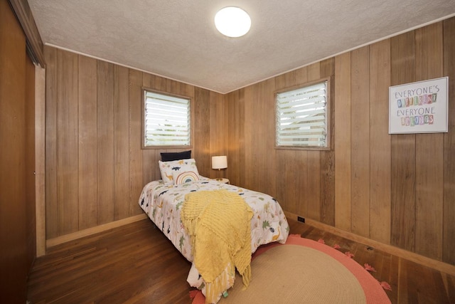 bedroom featuring dark hardwood / wood-style floors, a textured ceiling, and wood walls