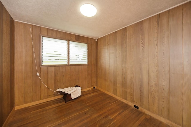 unfurnished room featuring dark hardwood / wood-style floors, a textured ceiling, and wood walls