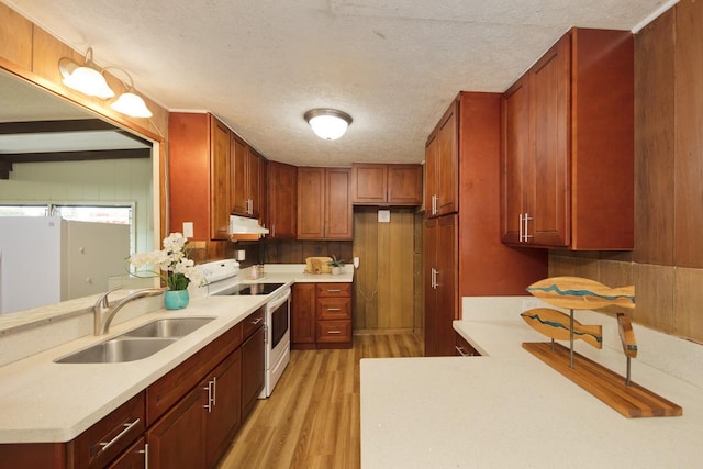 kitchen featuring sink, a textured ceiling, kitchen peninsula, white range with electric cooktop, and light hardwood / wood-style floors