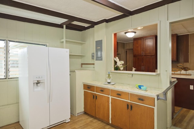 kitchen featuring beam ceiling, electric panel, white fridge with ice dispenser, and light wood-type flooring