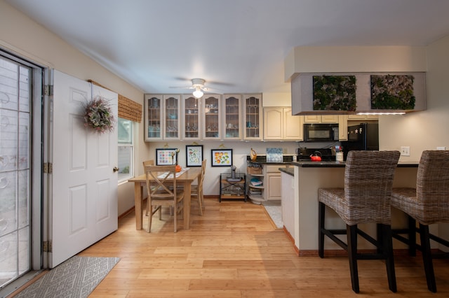 kitchen with kitchen peninsula, light hardwood / wood-style flooring, ceiling fan, and black appliances