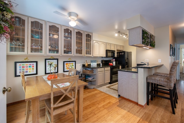 kitchen featuring ceiling fan, sink, kitchen peninsula, light hardwood / wood-style floors, and black appliances