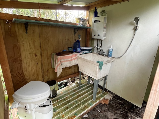 bathroom with tankless water heater and toilet