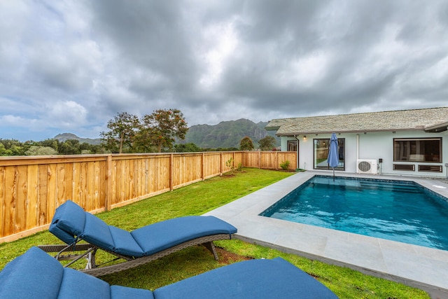 view of swimming pool with a patio, a lawn, a mountain view, and ac unit