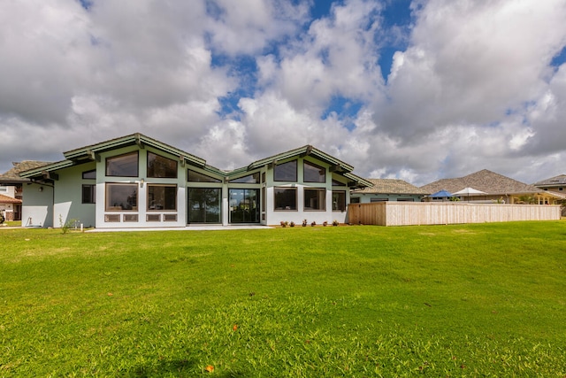 rear view of house with a lawn and a sunroom