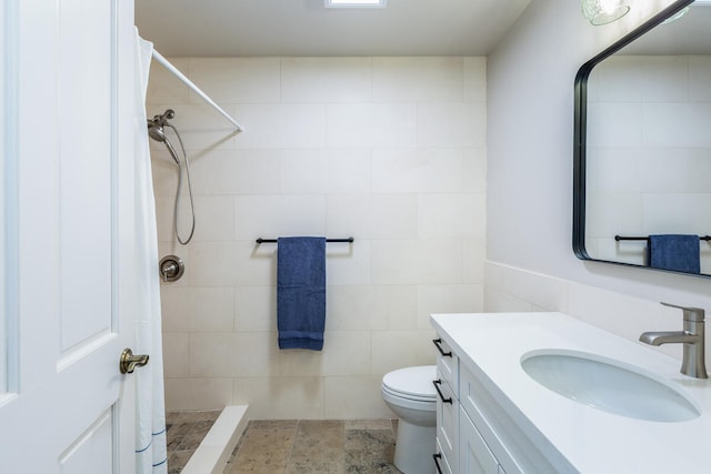 bathroom with tile walls, toilet, vanity, and a tile shower