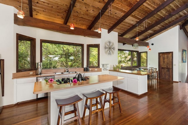 kitchen with beam ceiling, white cabinetry, a center island, wooden ceiling, and stainless steel appliances