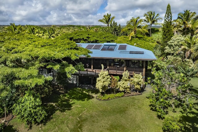 rear view of property featuring a yard, a deck, and solar panels