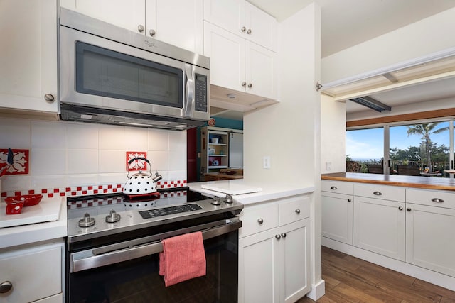 kitchen featuring white cabinets, appliances with stainless steel finishes, hardwood / wood-style flooring, and tasteful backsplash