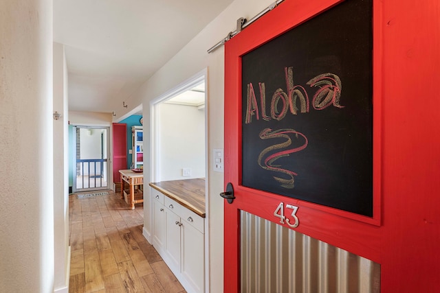 corridor featuring a barn door and light hardwood / wood-style flooring