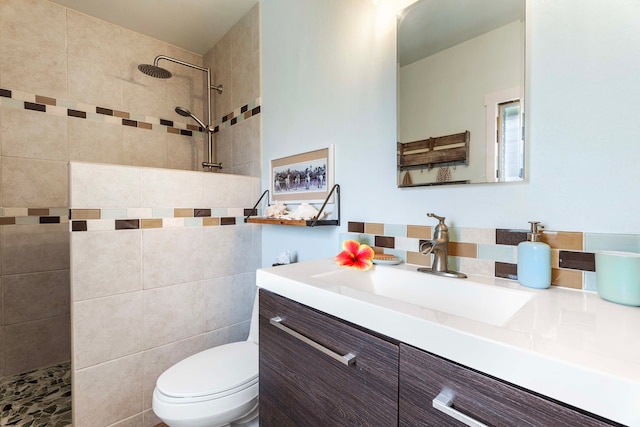 bathroom featuring a tile shower, vanity, and toilet