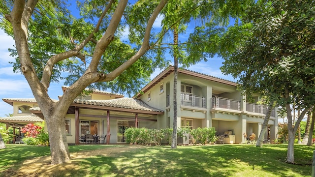 rear view of property with a lawn, a patio, and a balcony