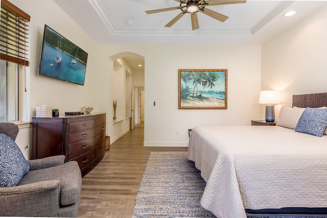 bedroom featuring ornamental molding, hardwood / wood-style floors, ceiling fan, and a tray ceiling