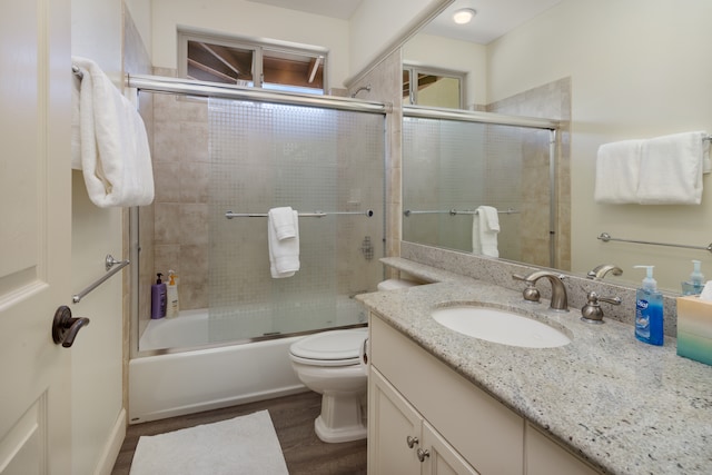 full bathroom featuring toilet, vanity, bath / shower combo with glass door, and hardwood / wood-style flooring