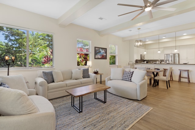 living room with light hardwood / wood-style flooring, beamed ceiling, and ceiling fan