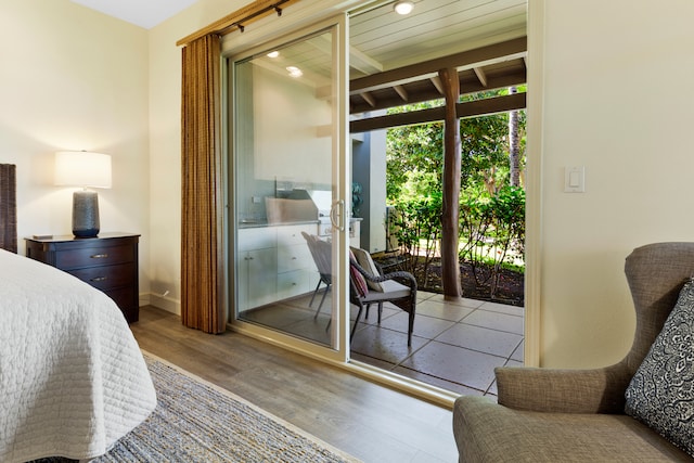 bedroom with light hardwood / wood-style floors, access to exterior, and a wall of windows