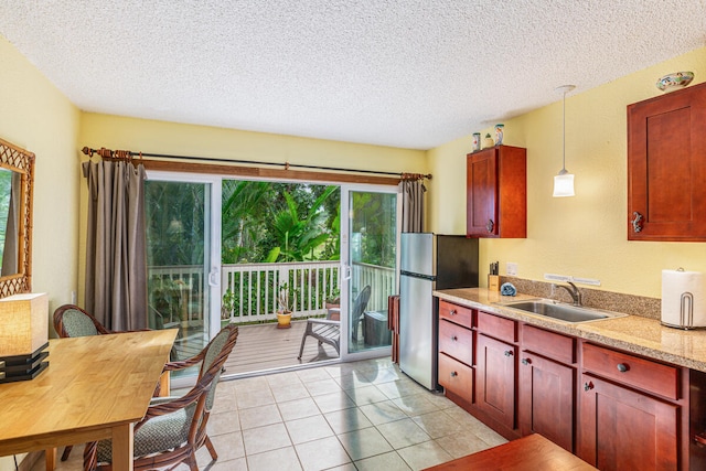 kitchen with sink, stainless steel fridge, a textured ceiling, decorative light fixtures, and light tile patterned floors