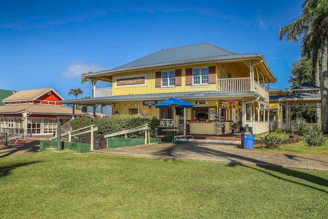 back of property with a patio area, a yard, and a balcony