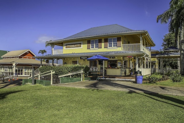 rear view of property featuring a yard and a balcony