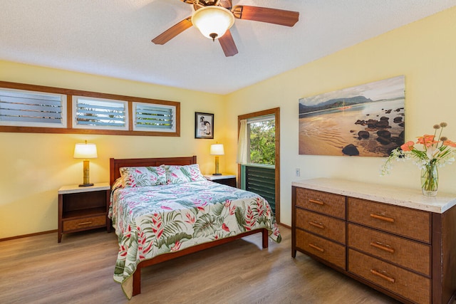 bedroom with ceiling fan, wood-type flooring, and a textured ceiling