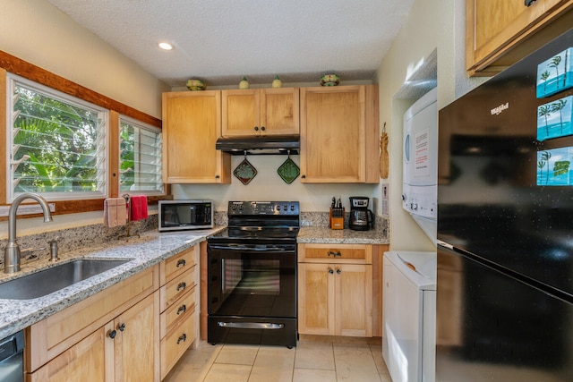 kitchen with sink, stacked washing maching and dryer, a textured ceiling, light brown cabinetry, and black appliances