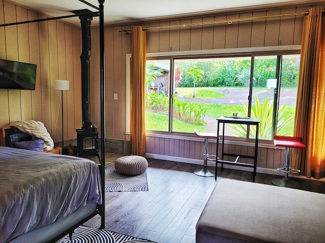 bedroom with a wood stove, hardwood / wood-style floors, and wooden walls