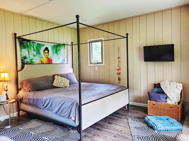 bedroom with wooden walls and hardwood / wood-style flooring