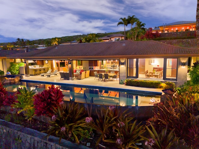 pool at dusk featuring outdoor lounge area and a patio